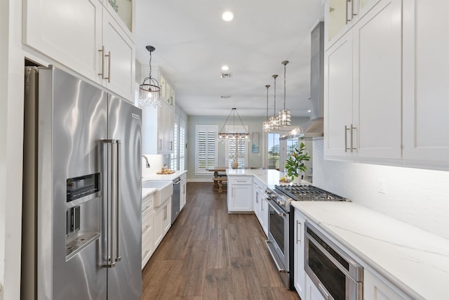 kitchen with white cabinets, premium appliances, pendant lighting, and light stone countertops