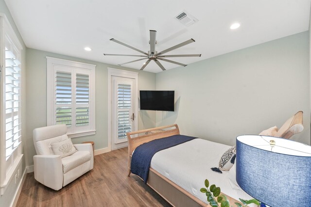 bedroom with multiple windows, hardwood / wood-style floors, and ceiling fan