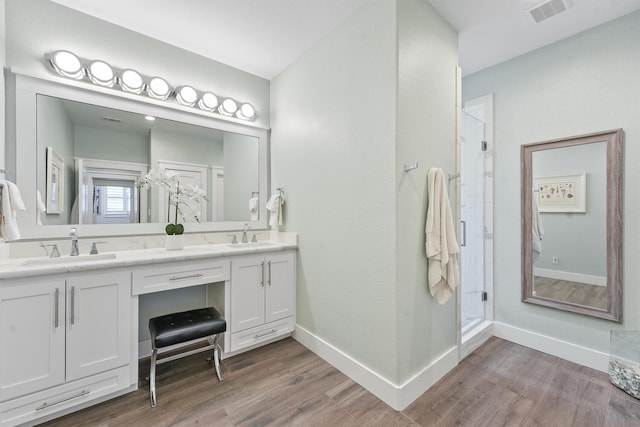 full bathroom with double vanity, wood finished floors, visible vents, and a stall shower