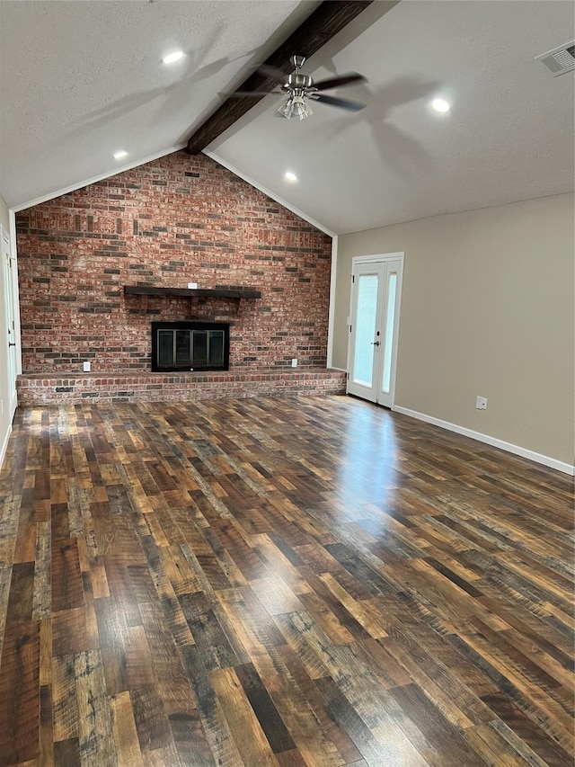 unfurnished living room featuring lofted ceiling with beams, a fireplace, dark wood-type flooring, and brick wall