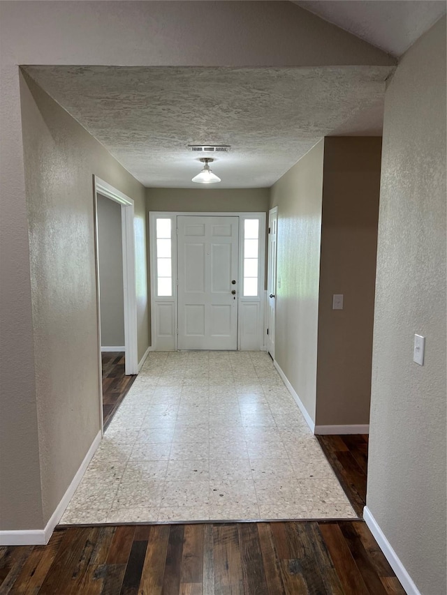 foyer entrance featuring hardwood / wood-style floors, plenty of natural light, and a textured ceiling