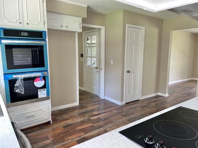 kitchen featuring stainless steel double oven, cooktop, dark hardwood / wood-style flooring, a textured ceiling, and white cabinets