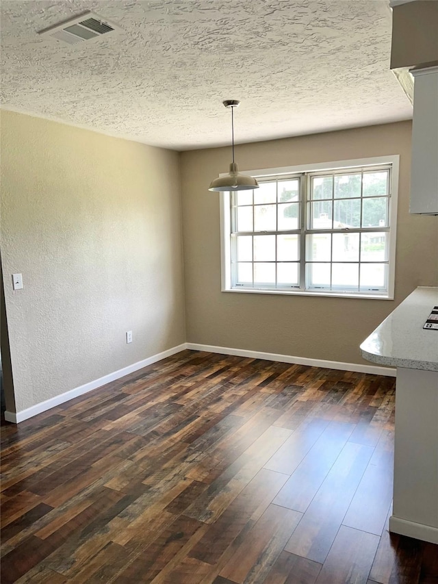 unfurnished dining area with a textured ceiling and dark hardwood / wood-style floors