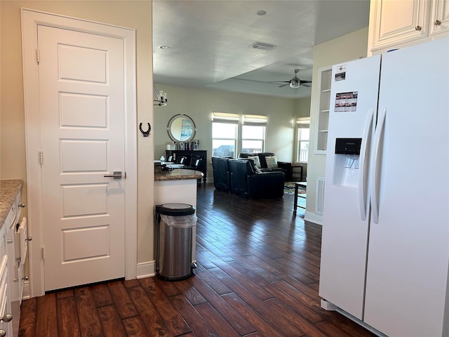 kitchen featuring white cabinetry, ceiling fan, dark wood-type flooring, white refrigerator with ice dispenser, and dark stone counters