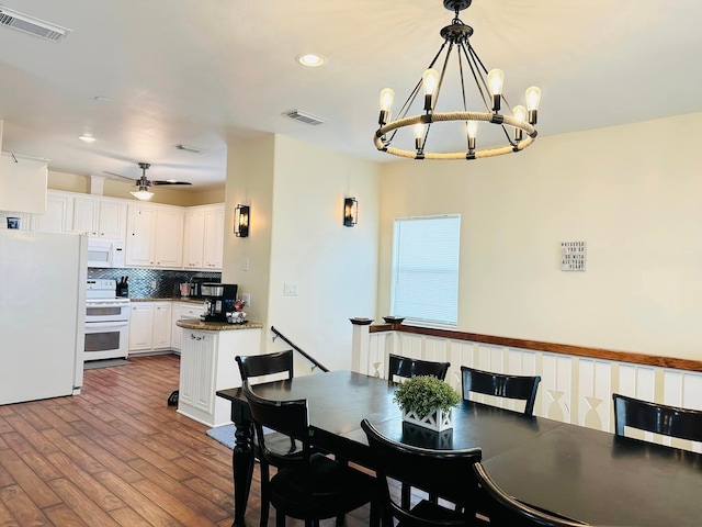 dining area with wood-type flooring and ceiling fan with notable chandelier