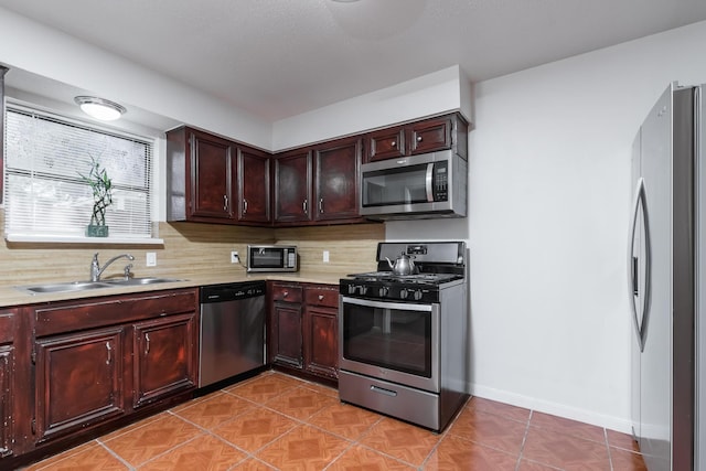 kitchen with backsplash, sink, light tile patterned flooring, and appliances with stainless steel finishes