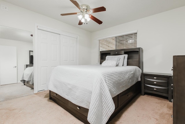 bedroom with ceiling fan, light carpet, and a closet