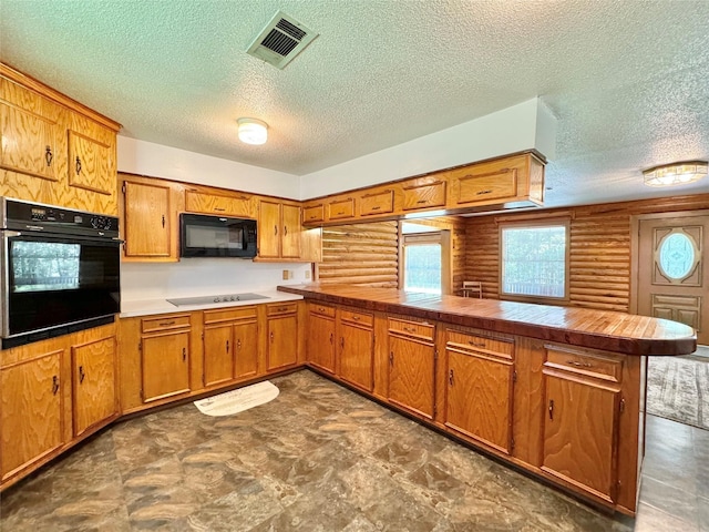 kitchen with kitchen peninsula, a textured ceiling, and black appliances