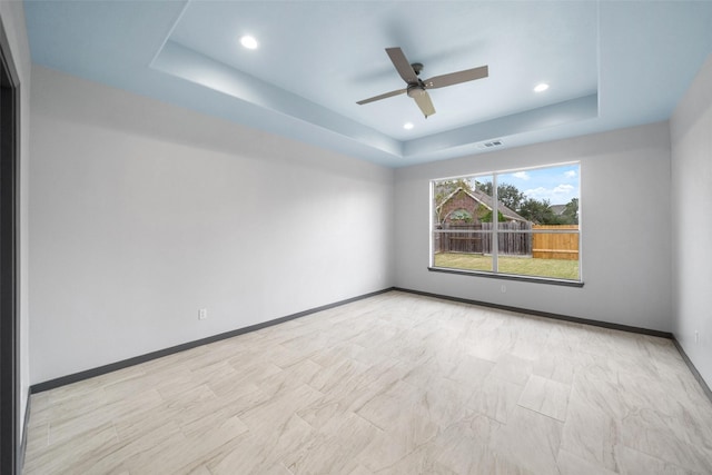 spare room with a raised ceiling and ceiling fan