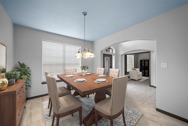 dining area with light wood-type flooring and an inviting chandelier