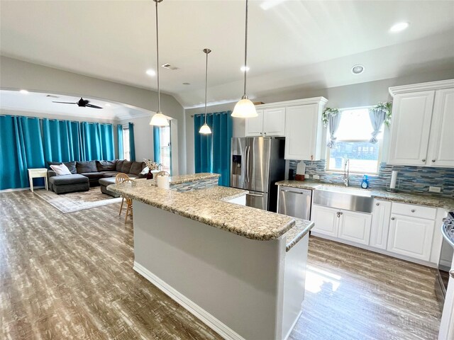 kitchen with appliances with stainless steel finishes, backsplash, ceiling fan, sink, and decorative light fixtures