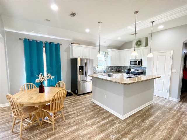 kitchen with appliances with stainless steel finishes, light wood-type flooring, light stone counters, white cabinets, and lofted ceiling