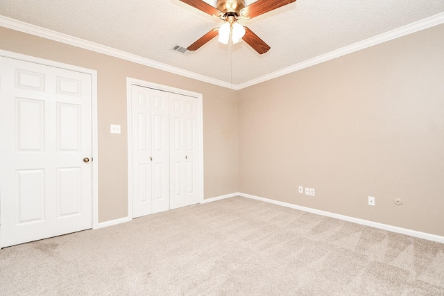 unfurnished bedroom with light carpet, a textured ceiling, ornamental molding, a closet, and ceiling fan