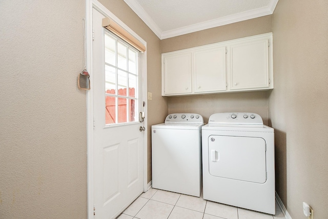 clothes washing area featuring cabinets, ornamental molding, light tile patterned floors, and washer and clothes dryer