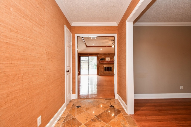 corridor with ornamental molding and a textured ceiling