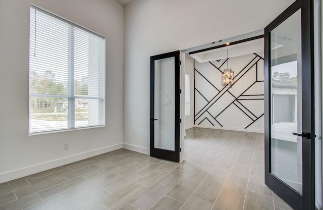 empty room with french doors, light hardwood / wood-style floors, and an inviting chandelier