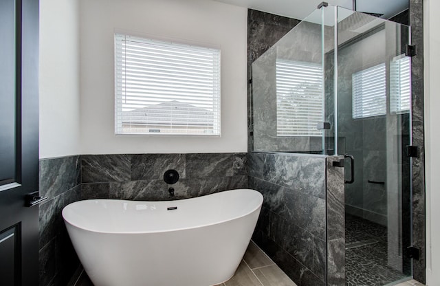 bathroom with separate shower and tub, a wealth of natural light, tile patterned flooring, and tile walls