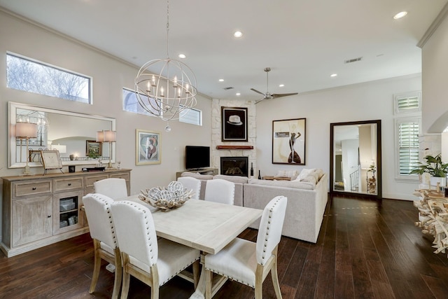 dining room with plenty of natural light, dark hardwood / wood-style flooring, a fireplace, and ceiling fan with notable chandelier