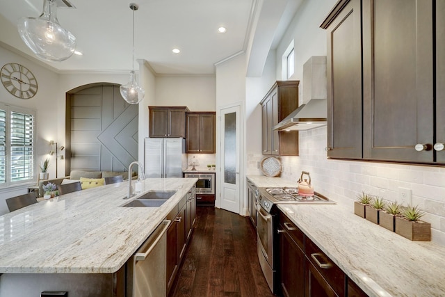 kitchen featuring sink, stainless steel appliances, light stone counters, crown molding, and a kitchen island with sink