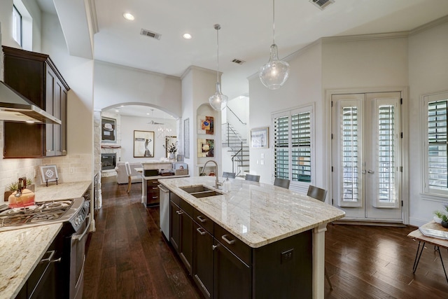 kitchen featuring stainless steel range, sink, hanging light fixtures, dark hardwood / wood-style flooring, and an island with sink