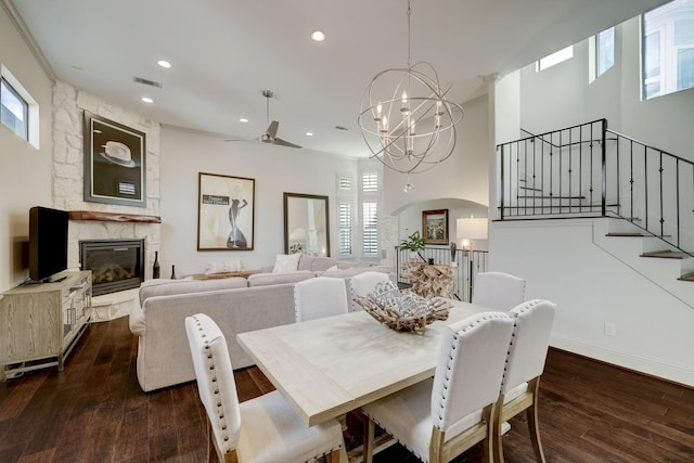 dining room with a fireplace, ceiling fan with notable chandelier, and dark hardwood / wood-style floors