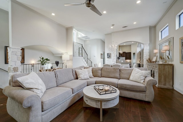 living room with dark hardwood / wood-style floors, crown molding, ceiling fan with notable chandelier, and decorative columns