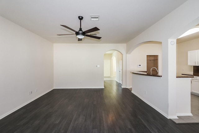 unfurnished living room with dark hardwood / wood-style flooring, ceiling fan, and sink