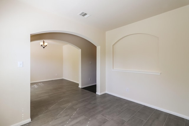 unfurnished room with an inviting chandelier and dark wood-type flooring