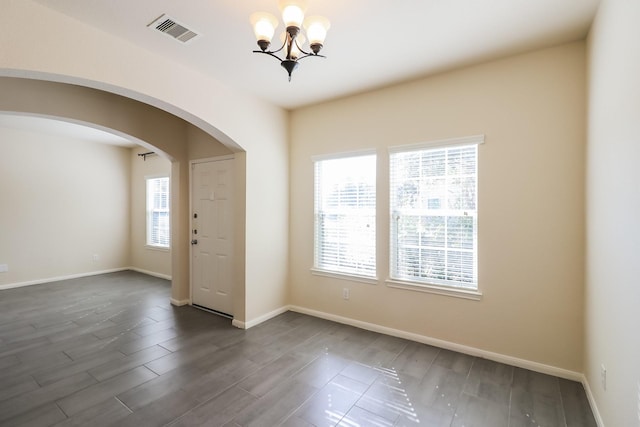 empty room with dark hardwood / wood-style flooring and an inviting chandelier