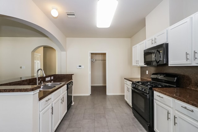 kitchen featuring sink, white cabinetry, dark stone countertops, and black appliances