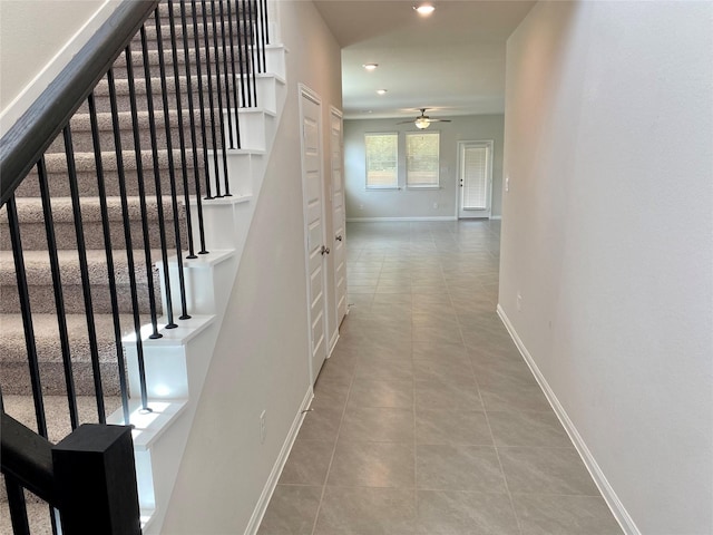 staircase featuring tile patterned floors and ceiling fan