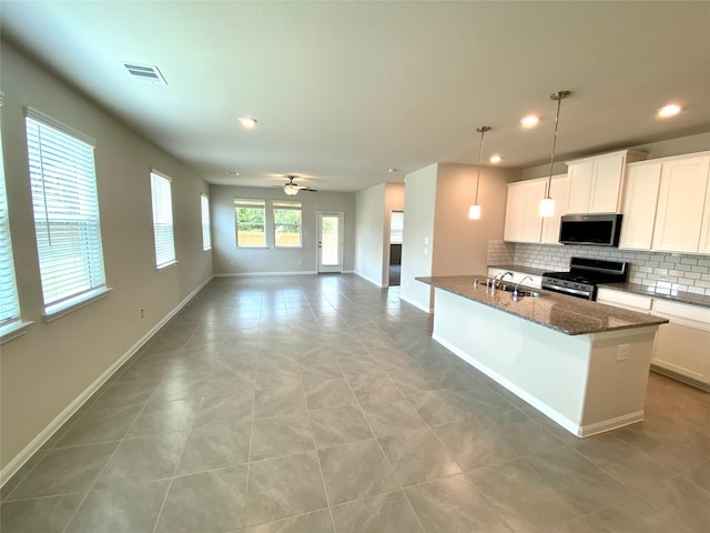 kitchen with appliances with stainless steel finishes, dark stone counters, ceiling fan, decorative light fixtures, and white cabinets