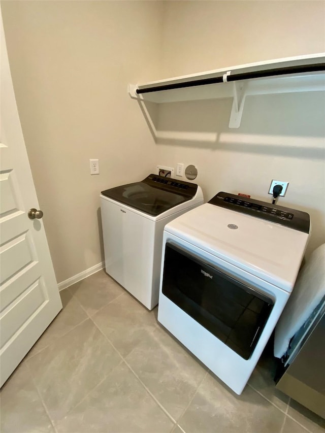 clothes washing area with light tile patterned floors and washer and clothes dryer