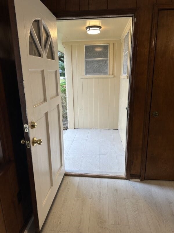 corridor with wooden walls and light hardwood / wood-style floors