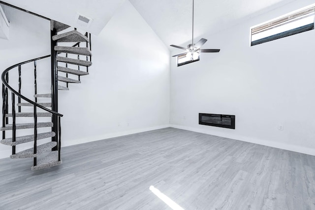 unfurnished living room featuring heating unit, ceiling fan, high vaulted ceiling, and wood-type flooring