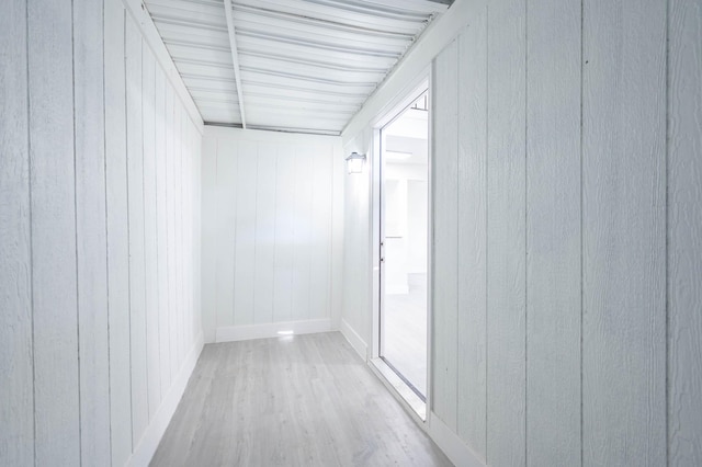 hallway with hardwood / wood-style flooring and wooden walls