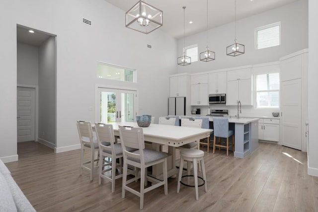 dining room featuring light hardwood / wood-style flooring, a towering ceiling, and sink