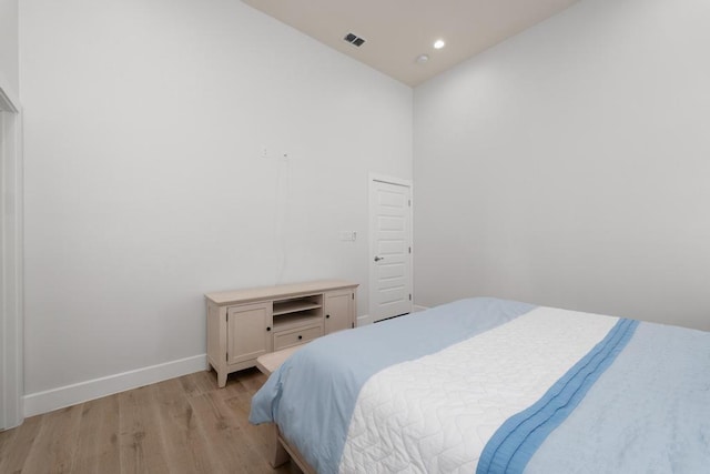 bedroom with a high ceiling and light wood-type flooring