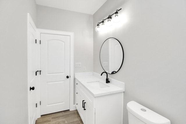 bathroom with hardwood / wood-style floors, vanity, and toilet