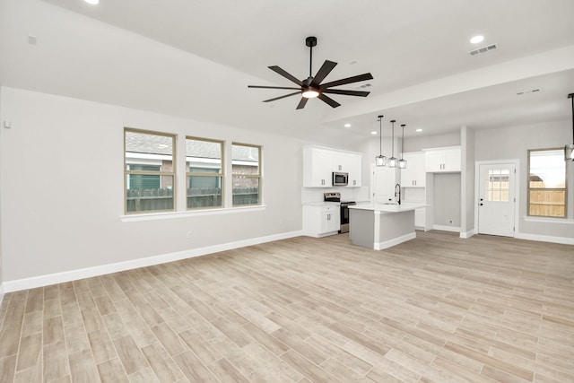 unfurnished living room featuring light hardwood / wood-style floors, ceiling fan, and sink