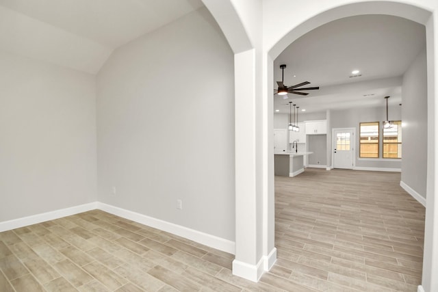 unfurnished room with ceiling fan, light wood-type flooring, sink, and lofted ceiling