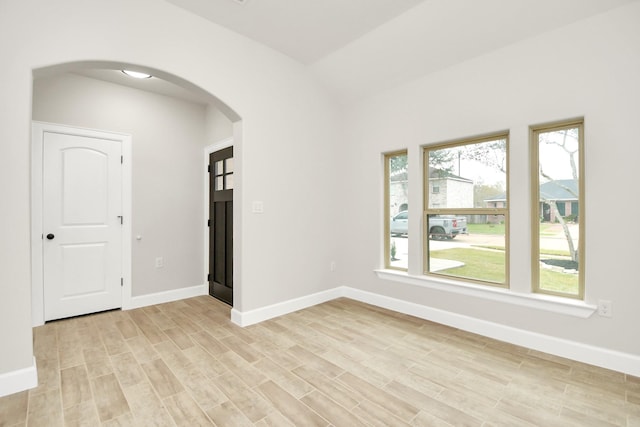 empty room with light hardwood / wood-style floors and lofted ceiling