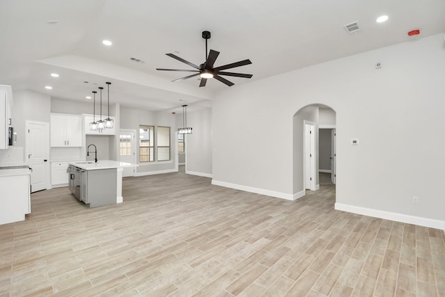 unfurnished living room with ceiling fan, sink, and light hardwood / wood-style flooring