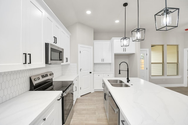 kitchen with sink, hanging light fixtures, tasteful backsplash, white cabinets, and appliances with stainless steel finishes