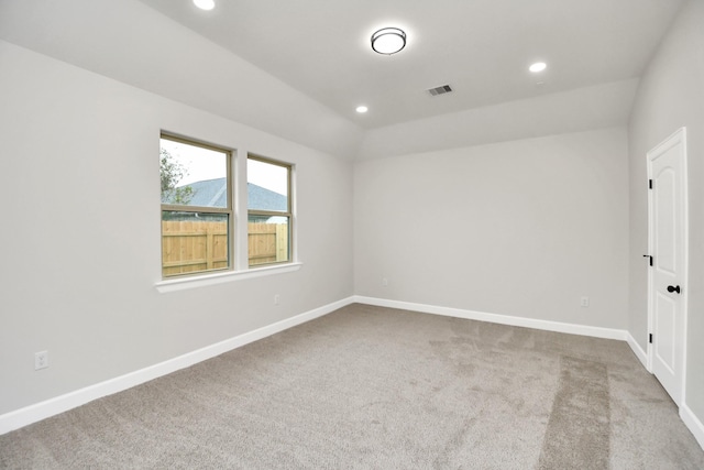 carpeted empty room with lofted ceiling