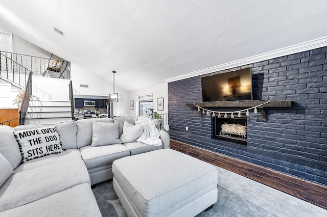 living room with wood-type flooring, a textured ceiling, a brick fireplace, and lofted ceiling