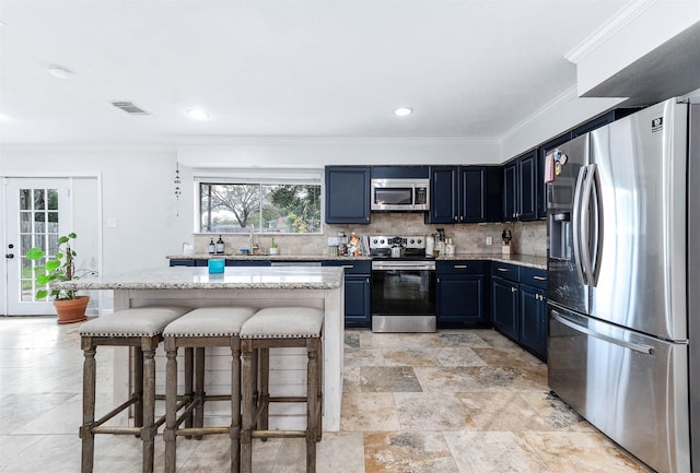 kitchen featuring stainless steel appliances, a kitchen breakfast bar, blue cabinets, crown molding, and decorative backsplash