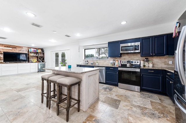 kitchen with a center island, crown molding, blue cabinetry, stainless steel appliances, and beverage cooler