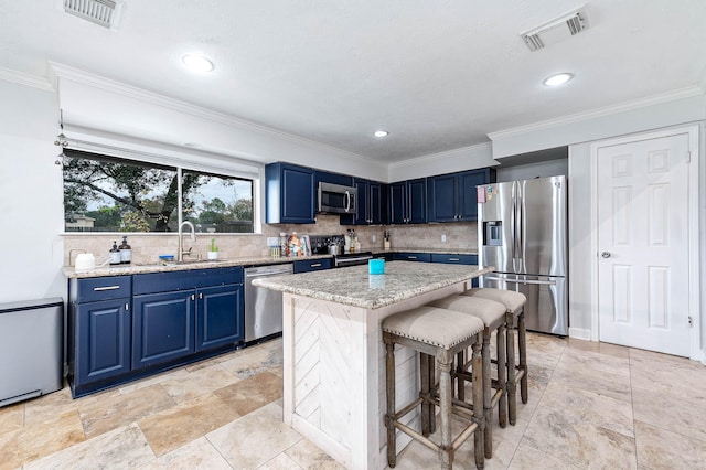 kitchen with appliances with stainless steel finishes, ornamental molding, sink, blue cabinetry, and a center island