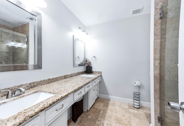 bathroom featuring a textured ceiling, vanity, and a shower with shower door